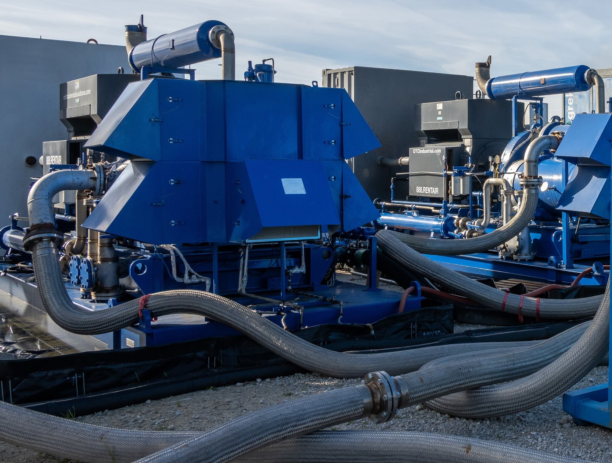 Large air compressor with cables running across to other industrial equipment