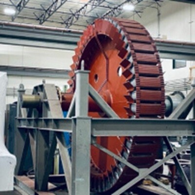 Large red industrial wheel with teeth in a factory setting.